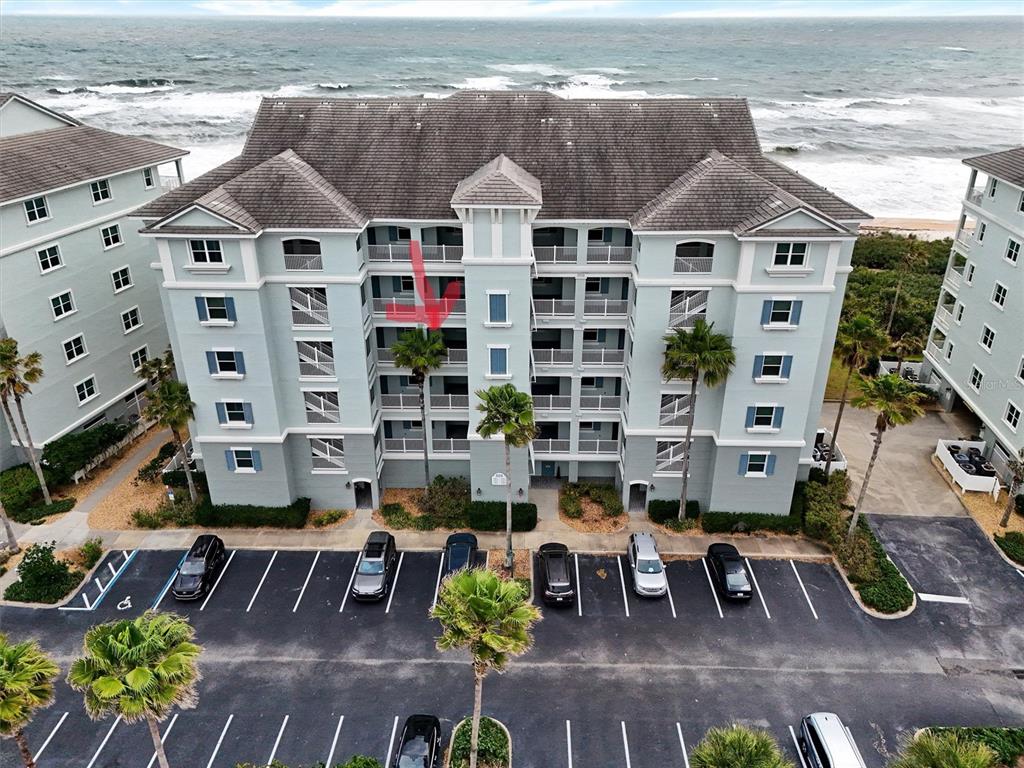 An aerial view shows a multi-story oceanfront condominium building with a parking lot in front — 800 CINNAMON BEACH WAY UNIT 742, PALM COAST, FL