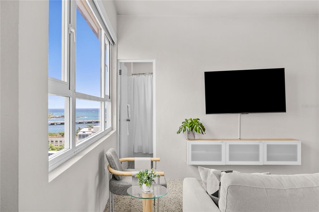 A living room features a wall-mounted television, a white media console, and ocean views — 603 MIRAMAR AVENUE UNIT 7, SAN JUAN, PR