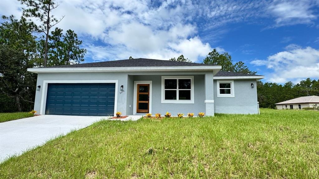 A single-story house with a gray exterior, a dark garage door, and a front lawn — 9278 N SATINWOOD TERRACE, CITRUS SPRINGS, FL