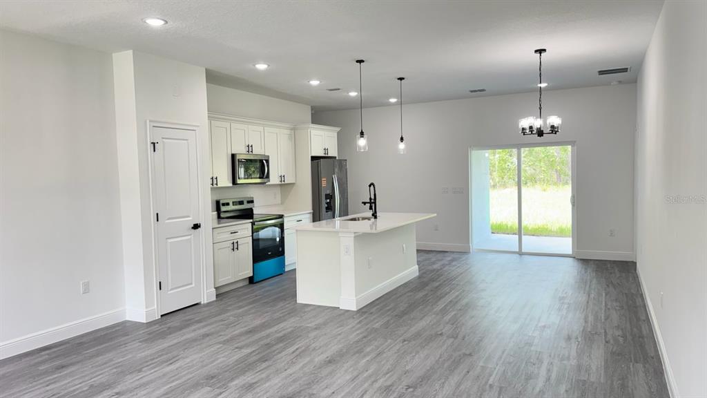 A modern kitchen with white cabinetry, a center island, and gray wood-look flooring — 9278 N SATINWOOD TERRACE, CITRUS SPRINGS, FL