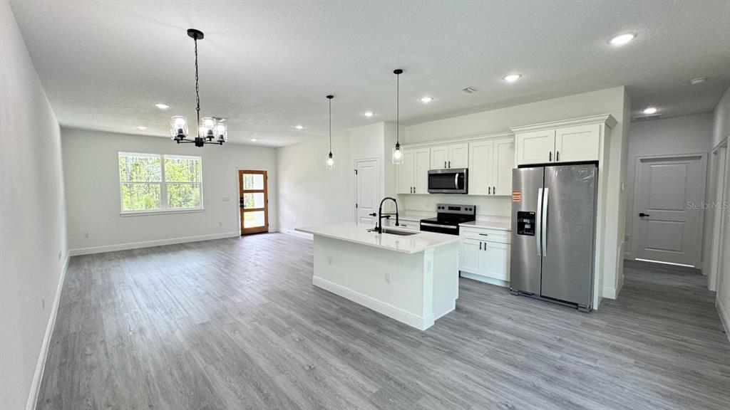An open-concept kitchen and living area features white cabinetry, a center island, and wood-look flooring — 9278 N SATINWOOD TERRACE, CITRUS SPRINGS, FL