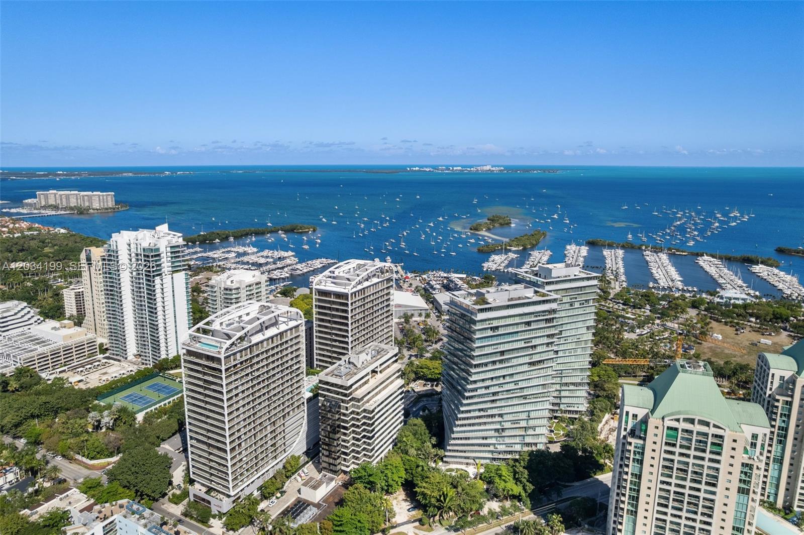 An aerial view shows several high-rise residential buildings near a marina and the ocean — 2655 S Bayshore Dr # 1911, Miami FL 33133, MIAMI, FL