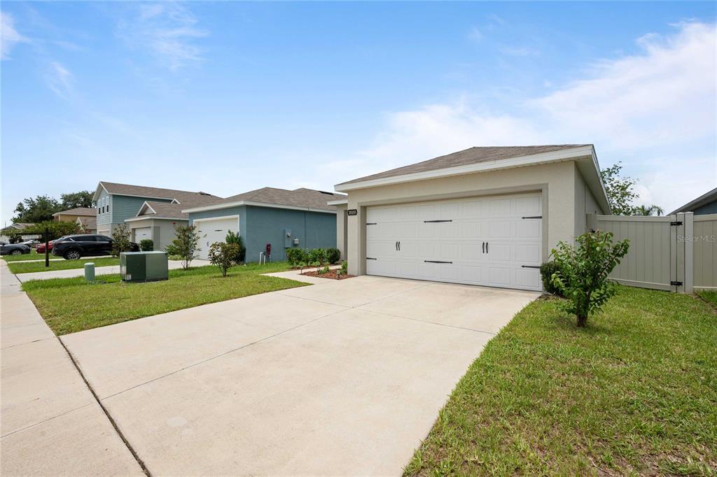 A concrete driveway leads to the white garage door of a single-story suburban house — 35155 JOMAR AVENUE, ZEPHYRHILLS, FL
