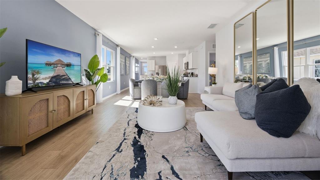 A living room features a light wood media console, white sofa, and a patterned rug — 3056 HOUSE FINCH ROAD, ST CLOUD, FL