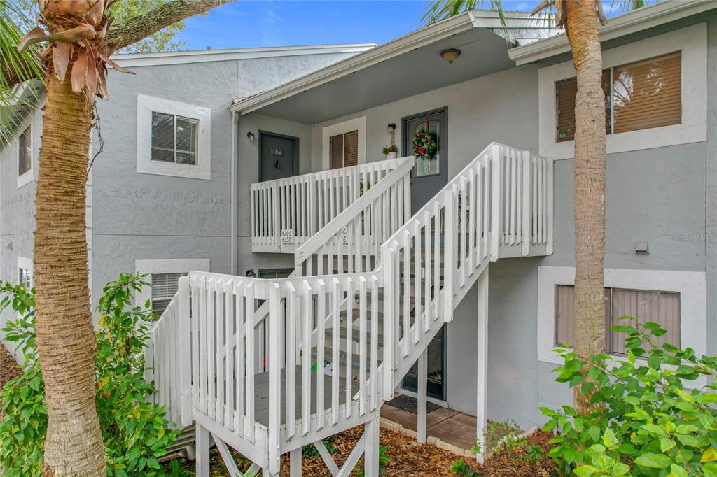 A two-story apartment building exterior features a white wooden staircase leading to an upper landing — 4166 PLANTATION COVE DRIVE UNIT 505, ORLANDO, FL