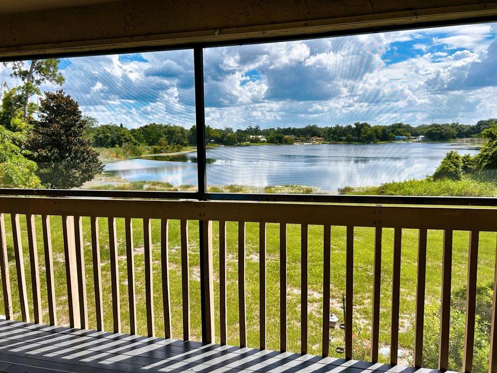 A screened-in porch overlooks a grassy lawn and a lake under a cloudy sky — 4166 PLANTATION COVE DRIVE UNIT 505, ORLANDO, FL
