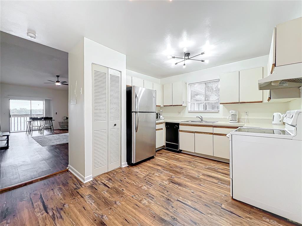 A kitchen features stainless steel appliances, white cabinets, and wood-look flooring — 4166 PLANTATION COVE DRIVE UNIT 505, ORLANDO, FL