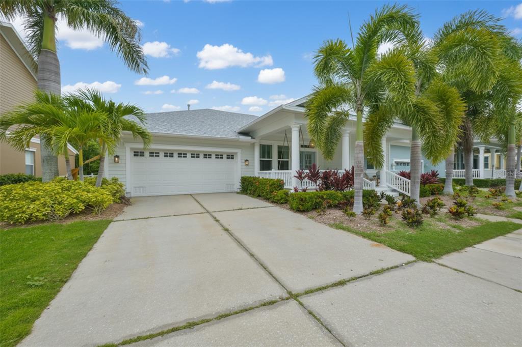 A single-story house with a white garage, a front porch, and several palm trees — 404 ISLEBAY DRIVE, APOLLO BEACH, FL