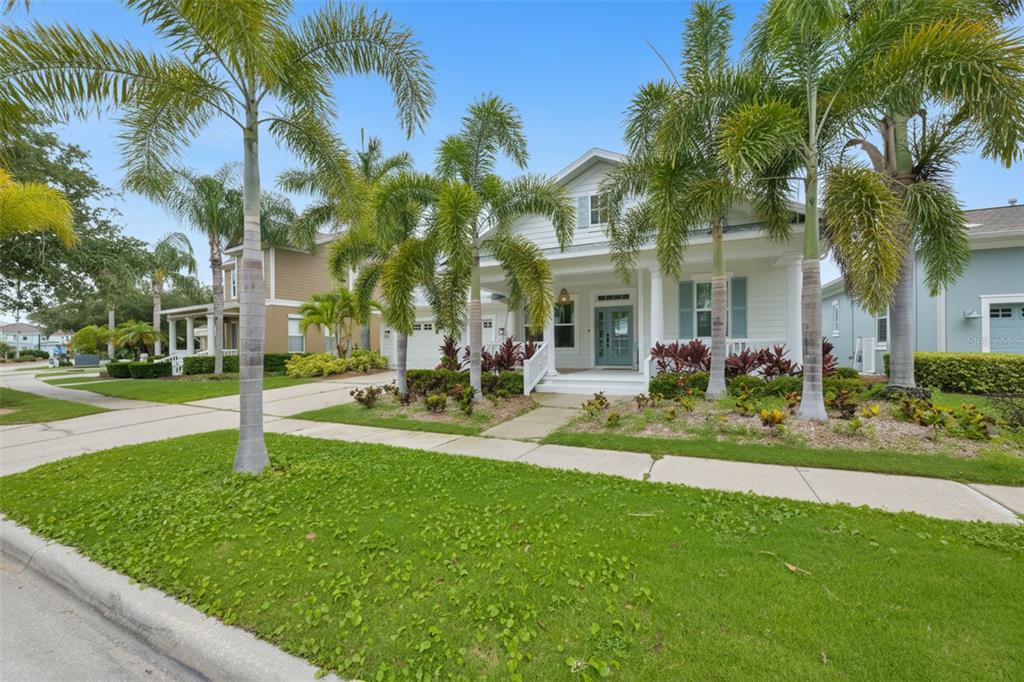 A white two-story house with a front porch and palm trees in the yard — 404 ISLEBAY DRIVE, APOLLO BEACH, FL