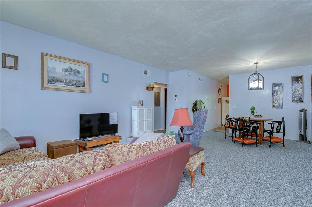 A living room and dining area feature light blue walls, carpeted floors, and traditional furniture — 4022 57TH STREET N UNIT 260, KENNETH CITY, FL
