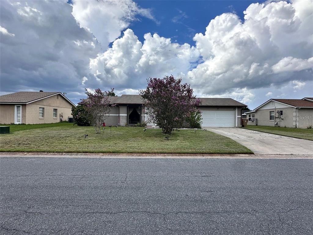A single-story suburban house with a two-car garage and two flowering trees in the yard — 263 LA PAZ DRIVE, KISSIMMEE, FL