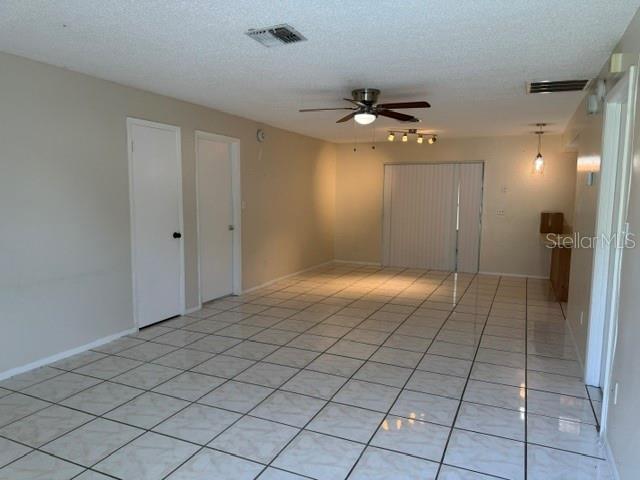 A living area with light-colored tile flooring, a ceiling fan, and two closed doors — 263 LA PAZ DRIVE, KISSIMMEE, FL