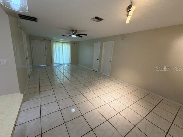 An empty room features white tiled flooring, a ceiling fan, and two closed interior doors — 263 LA PAZ DRIVE, KISSIMMEE, FL