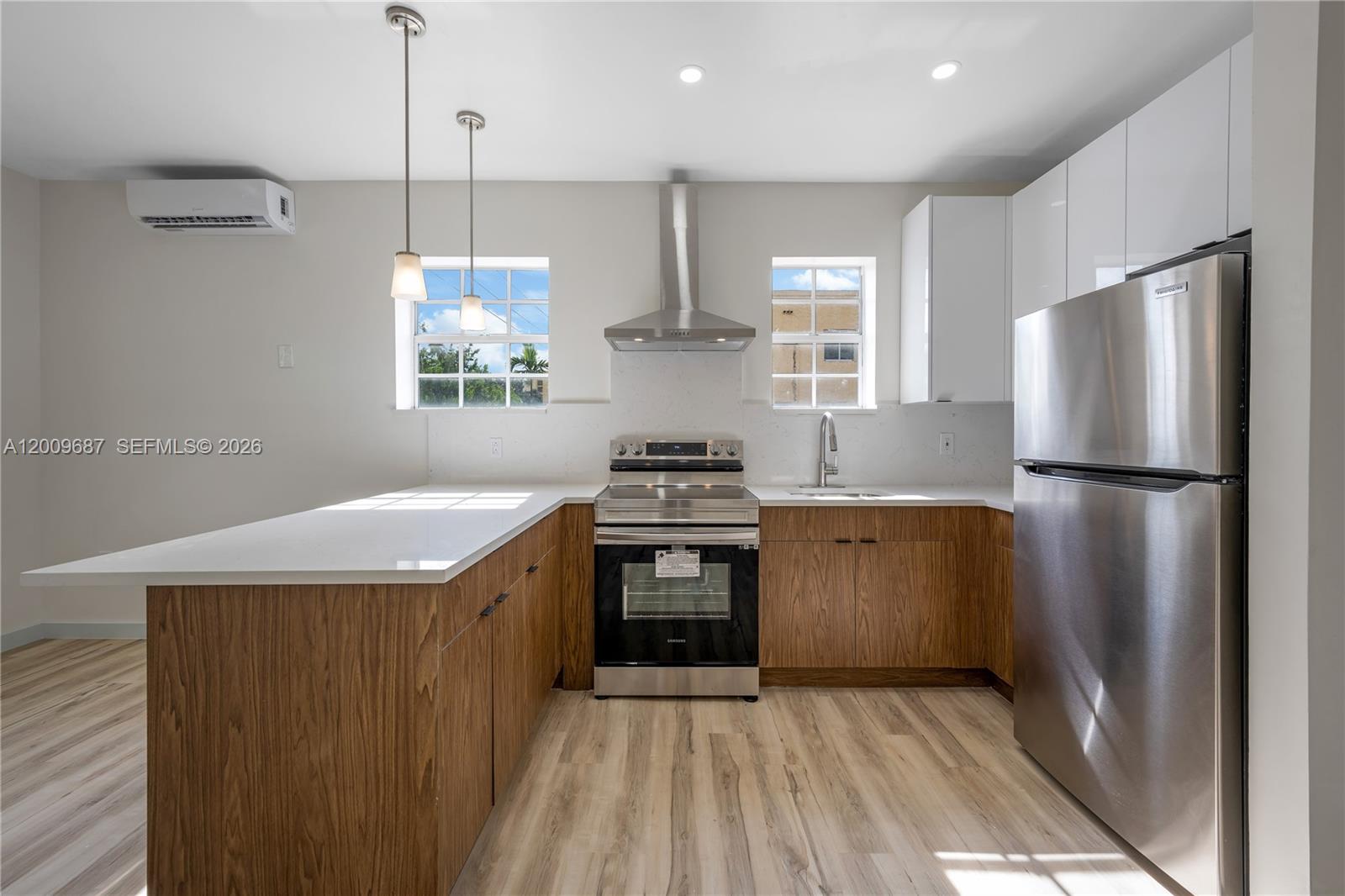 A kitchen features wood-grain lower cabinets, white upper cabinets, stainless steel appliances, and quartz countertops — 1132 NW 3rd St, Miami FL 33128, MIAMI, FL
