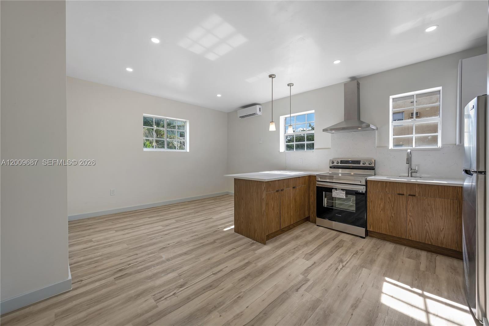 A kitchen features wood cabinets, stainless steel appliances, and light-colored wood-look flooring — 1132 NW 3rd St, Miami FL 33128, MIAMI, FL