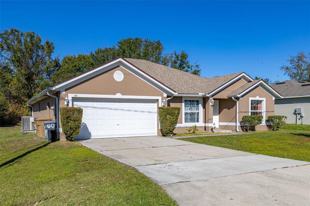 A tan single-story house with a white garage door and a concrete driveway — 60 ANDORA COURT, KISSIMMEE, FL