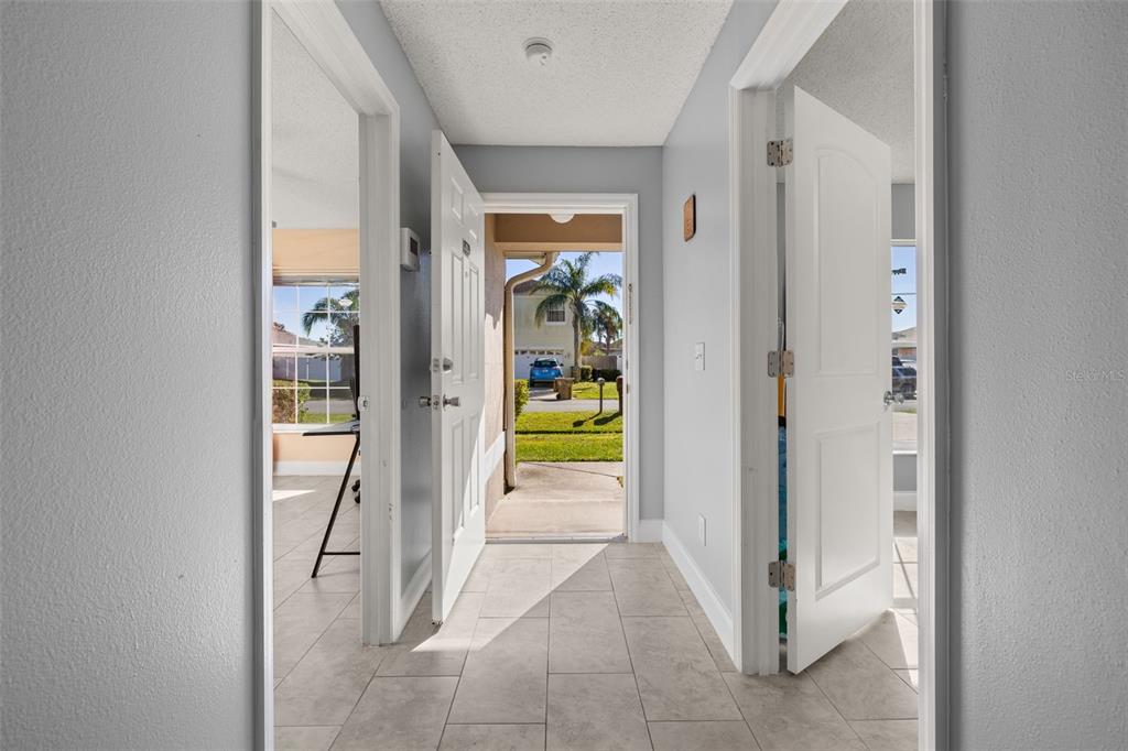 A tiled entryway leads to an open front door showing a driveway and palm tree — 60 ANDORA COURT, KISSIMMEE, FL