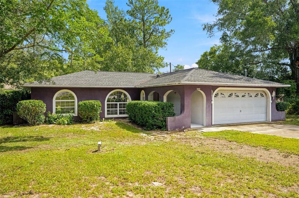 A single-story purple house with a two-car garage and arched windows sits on a lawn — 1325 W SORRENTO DRIVE, CITRUS SPRINGS, FL