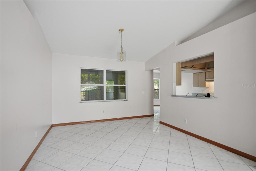 A dining room with white walls, tile flooring, a window, and a kitchen pass-through window — 1325 W SORRENTO DRIVE, CITRUS SPRINGS, FL