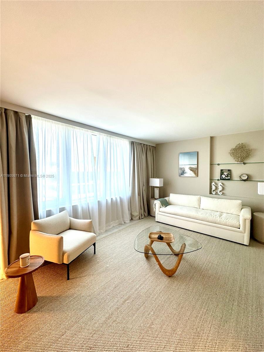 A living room features a white sofa, an armchair, and a glass-topped wooden coffee table — 2301 Collins Ave # 836, Miami Beach FL 33139, MIAMI BEACH, FL