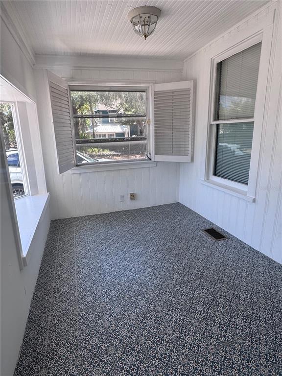 A sunroom features patterned tile flooring, white paneled walls, and windows with open shutters — 12 WEST ORANGE, TARPON SPRINGS, FL