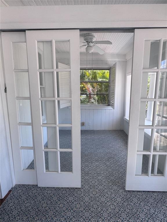 A sunroom with patterned carpet and white French doors opens to a view of trees — 12 WEST ORANGE, TARPON SPRINGS, FL