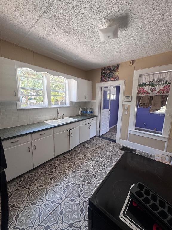 A kitchen features white cabinets, a double sink, patterned tile flooring, and a pass-through window — 12 WEST ORANGE, TARPON SPRINGS, FL