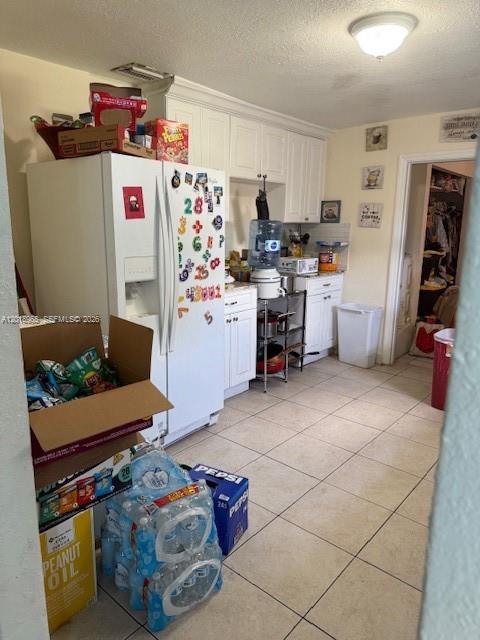 A kitchen features white cabinetry, a refrigerator covered in magnets, and tile flooring — 5328 SW 18TH ST, Hollywood FL 33023, HOLLYWOOD, FL
