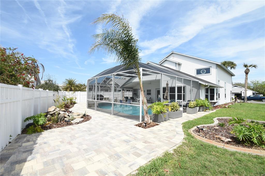 A backyard features a screened-in swimming pool, a paver patio, and a palm tree — 1 BEDFORD DRIVE, PALM COAST, FL