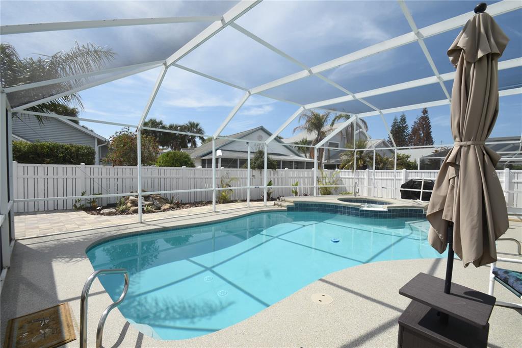 A swimming pool and spa are enclosed within a screened lanai in a backyard setting — 1 BEDFORD DRIVE, PALM COAST, FL