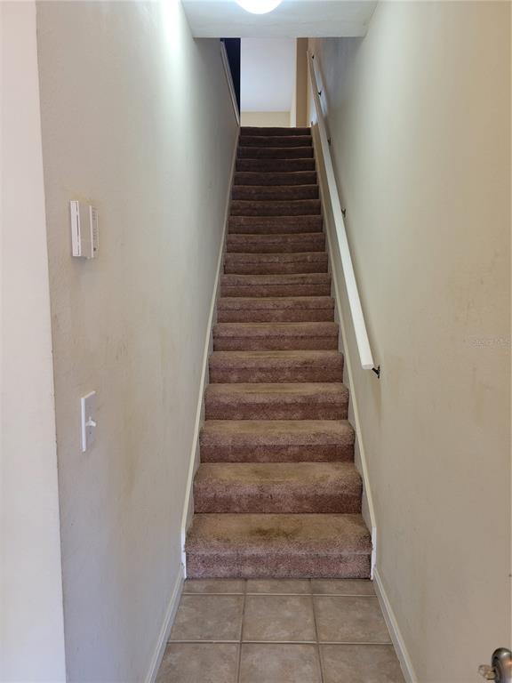 A straight staircase with brown carpet and a white handrail leads to an upper level — 2139 CHIANTI PLACE UNIT 5-0153, PALM HARBOR, FL