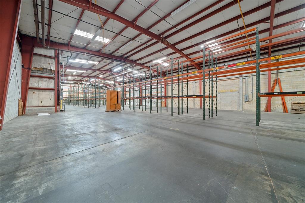 A large, empty warehouse space features concrete floors, exposed steel beams, and tall industrial shelving — 506 SE 3RD AVENUE, OCALA, FL