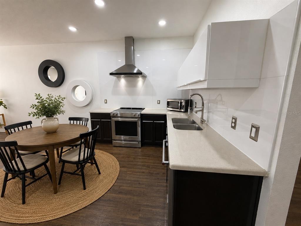 A modern kitchen features dark cabinets, white countertops, a stainless steel range, and a dining area — 12210 LANGSTAFF DRIVE, WINDERMERE, FL