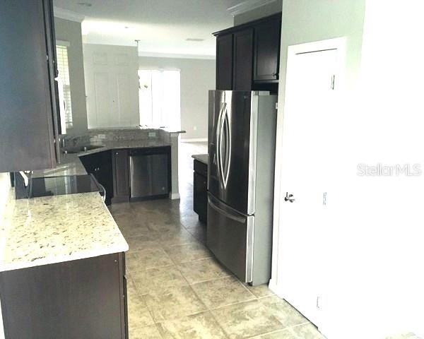 A kitchen features dark wood cabinets, granite countertops, stainless steel appliances, and tile flooring — 3603 SANCTUARY DRIVE, ST CLOUD, FL