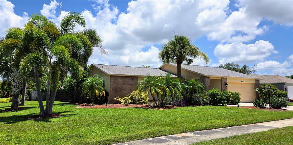 A single-story house with a brick facade and palm trees sits on a grassy lawn — 3803 EASTON STREET, SARASOTA, FL
