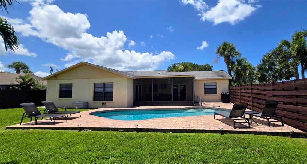 A backyard features a swimming pool, a paved patio, lounge chairs, and a house exterior — 3803 EASTON STREET, SARASOTA, FL