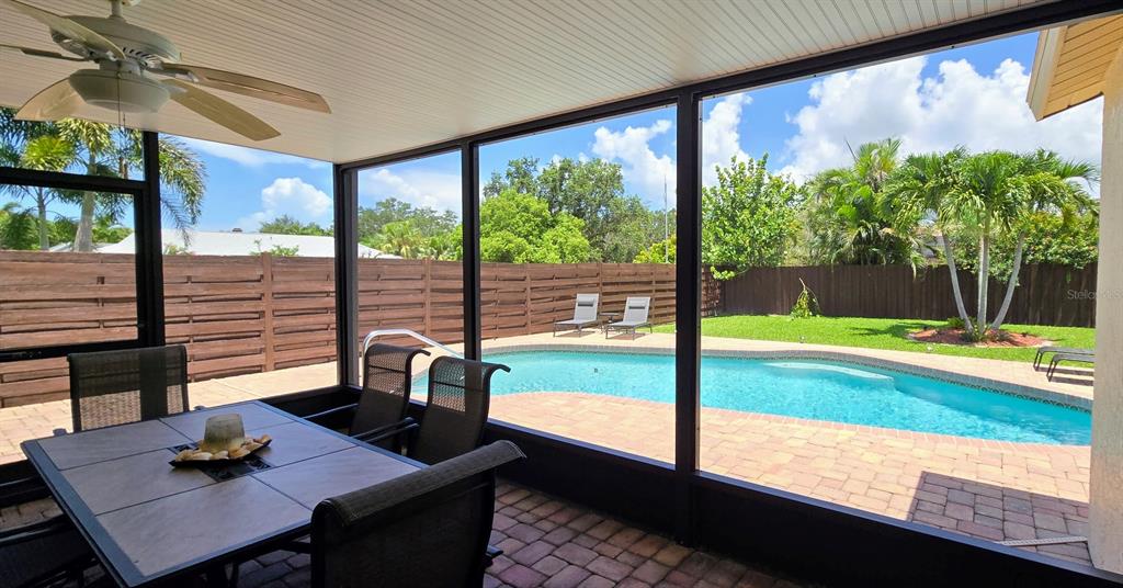 A screened-in patio features a dining set, ceiling fan, and a view of a swimming pool — 3803 EASTON STREET, SARASOTA, FL