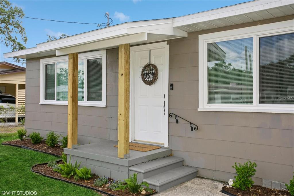 A gray house exterior features a white front door, wooden porch posts, and a concrete stoop — 1813 5TH STREET W, PALMETTO, FL