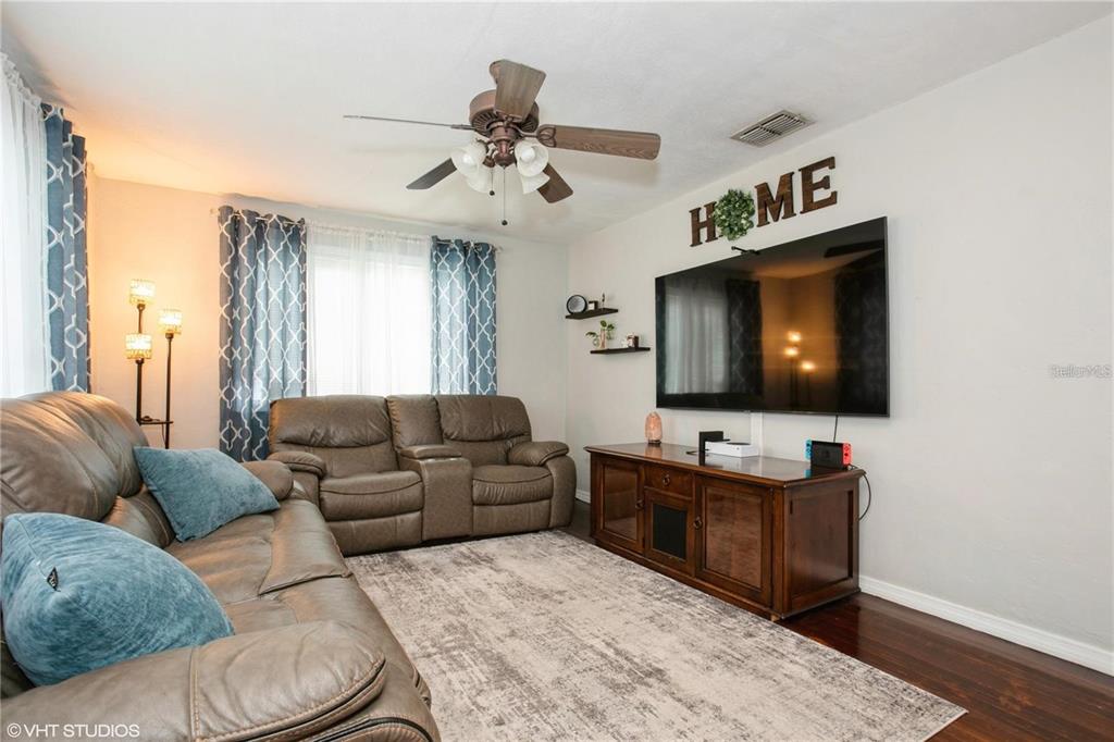 A living room features a brown leather sofa, a television, and a ceiling fan — 1813 5TH STREET W, PALMETTO, FL
