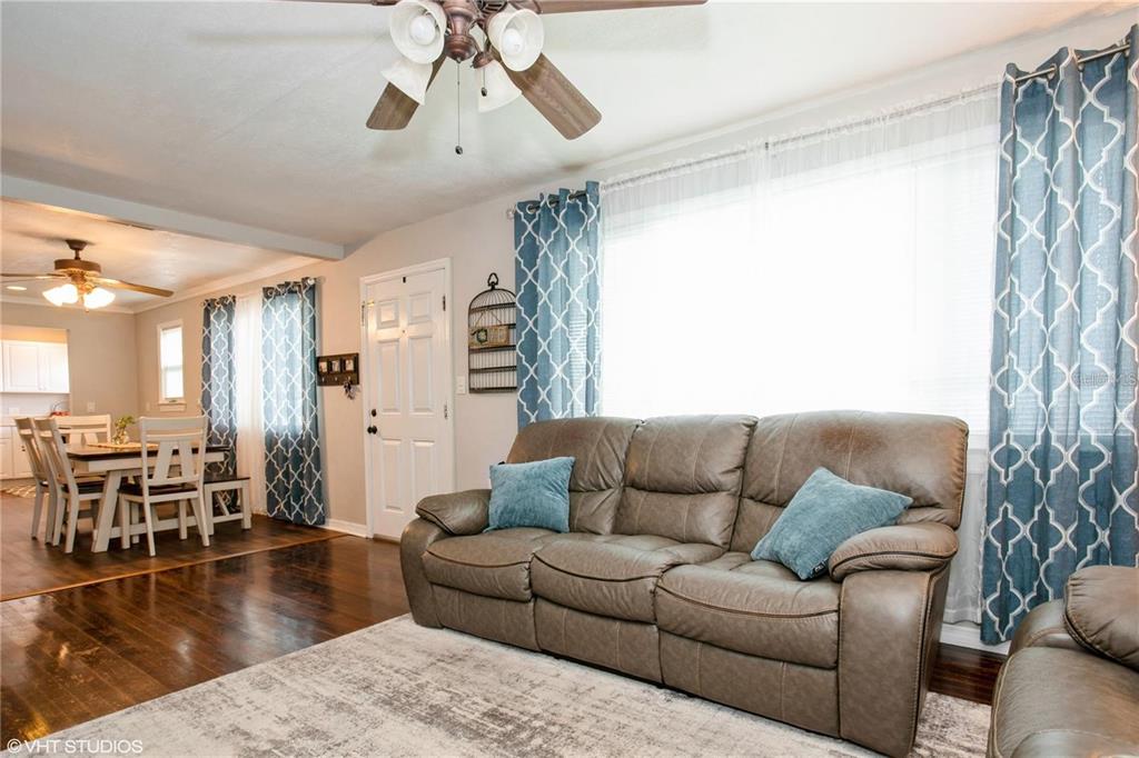 A living room features a brown leather sofa, hardwood floors, and a ceiling fan — 1813 5TH STREET W, PALMETTO, FL