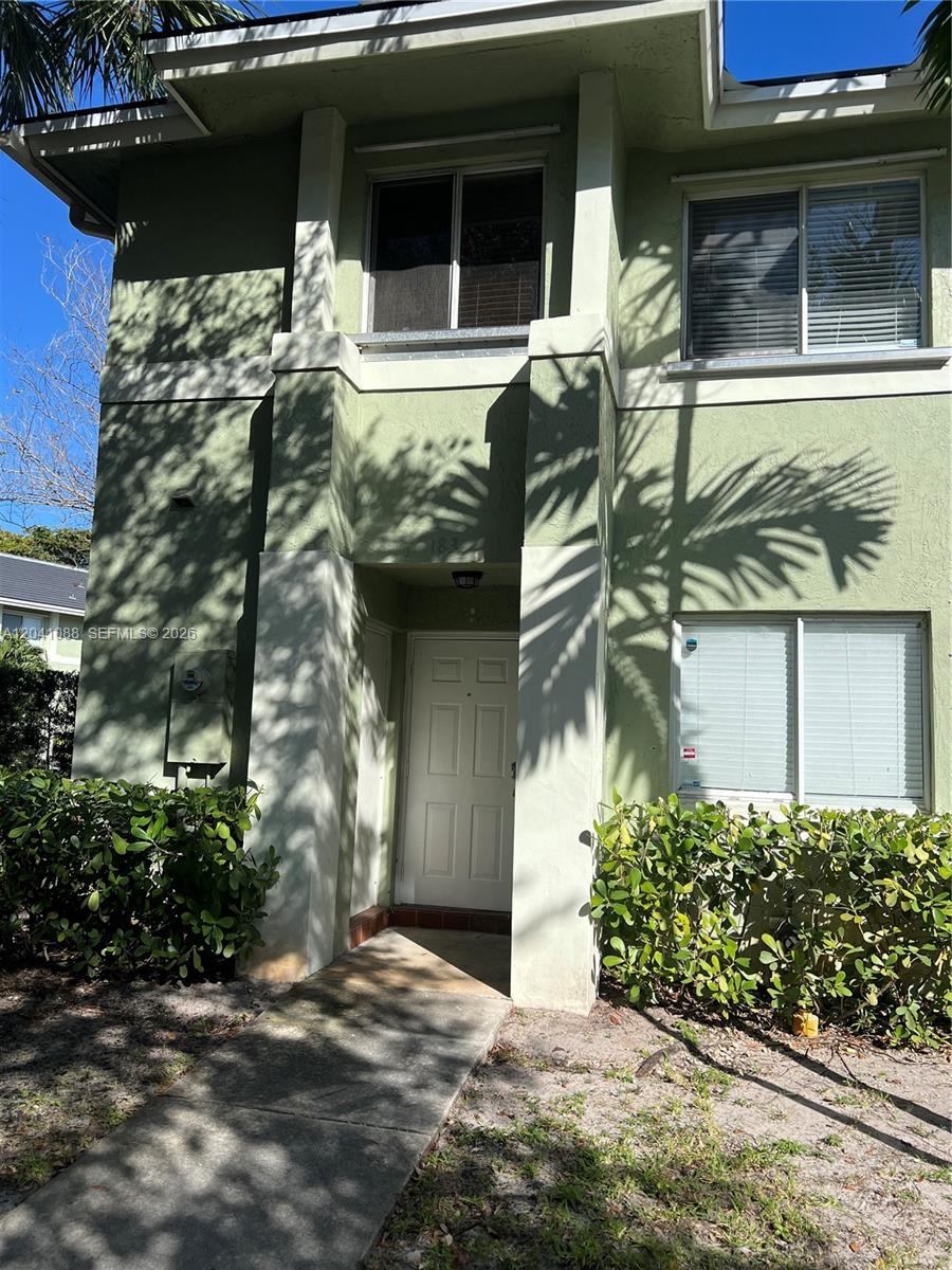 A two-story green stucco building features a recessed white front door and palm tree shadows — 183 Hidden Ct Rd # 33, Hollywood FL 33023, HOLLYWOOD, FL
