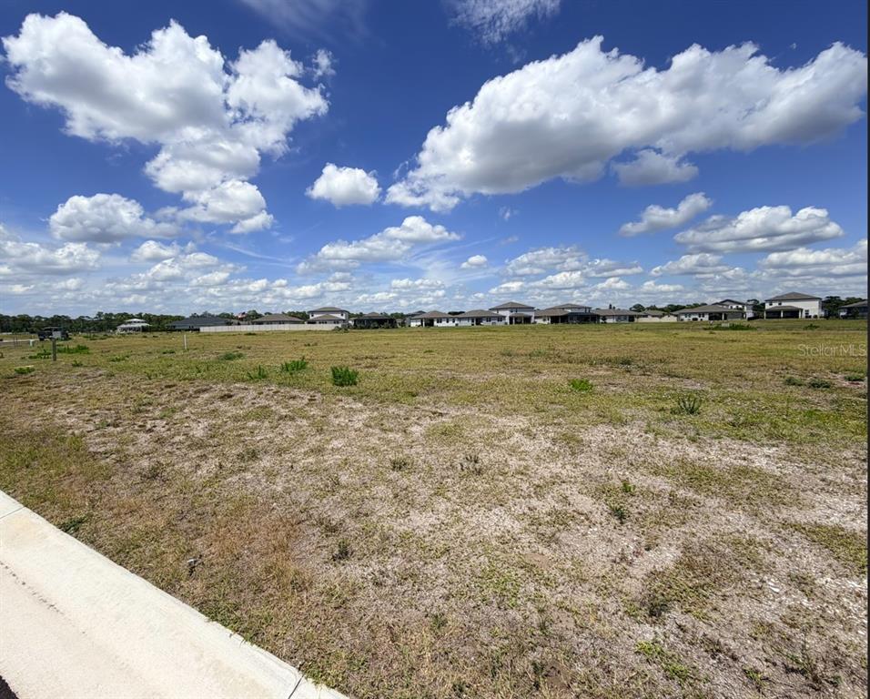 A vacant, grassy residential lot under a blue sky with scattered clouds — 254 HOLLY BANK AVENUE, NOKOMIS, FL