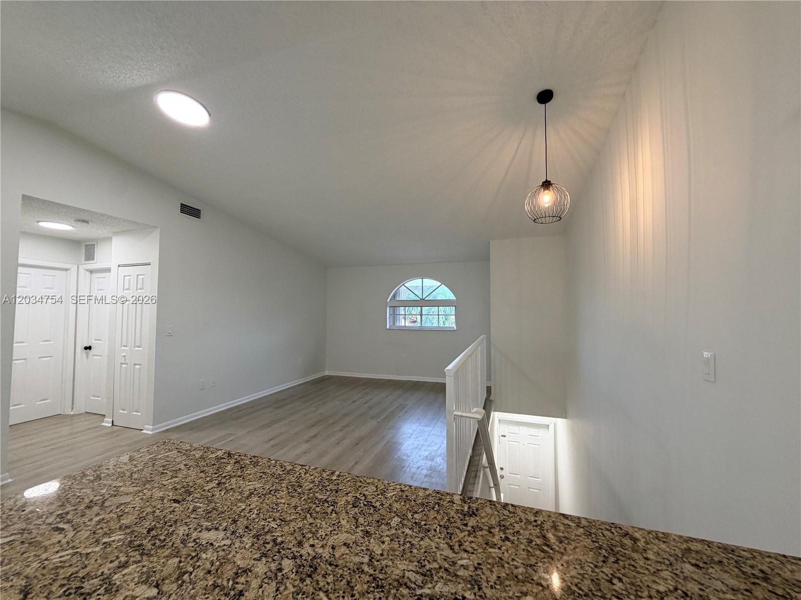 An elevated view shows a loft area with light wood flooring, white walls, and a pendant light — 7730 W 34th Ln # 202, Hialeah FL 33018, HIALEAH, FL