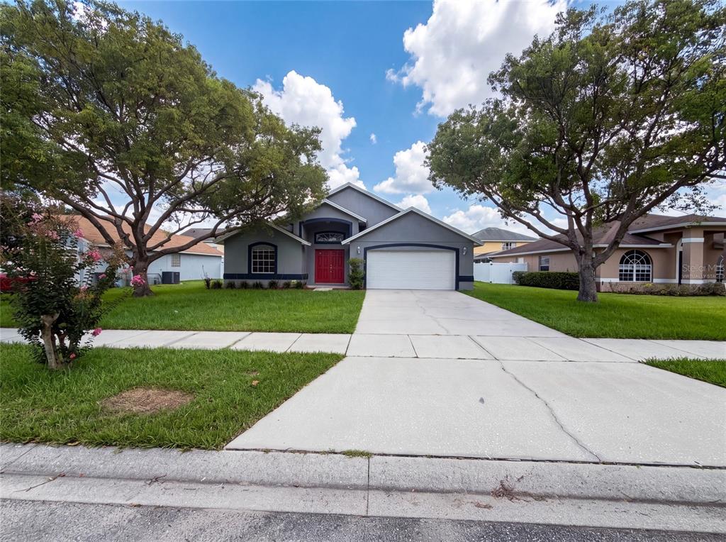 A single-story house with a gray exterior, a red front door, and a two-car garage — 721 SUNBURST COVE LANE, WINTER GARDEN, FL