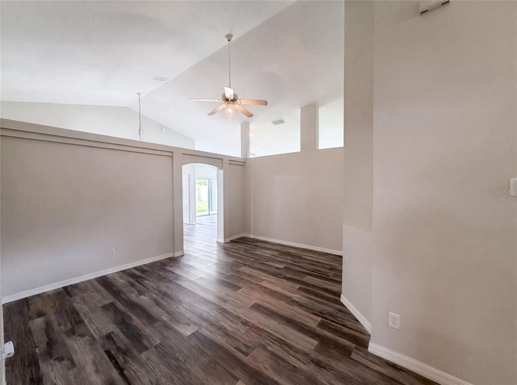 An empty room features vaulted ceilings, a ceiling fan, and wood-look flooring — 721 SUNBURST COVE LANE, WINTER GARDEN, FL