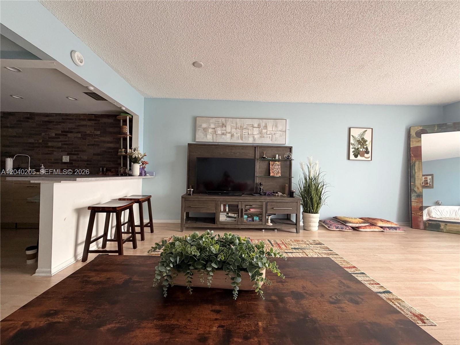 A living room features light blue walls, a wooden entertainment center, and a breakfast bar — 12500 NE 15th Ave # 312, North Miami FL 33161, NORTH MIAMI, FL