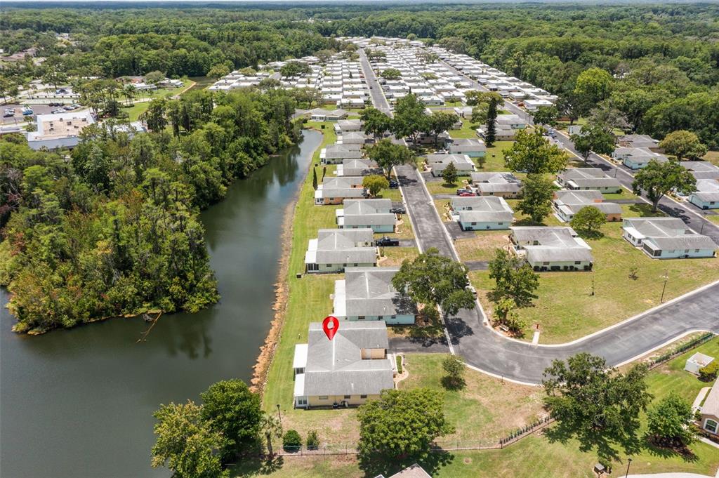 An aerial view shows a yellow house with a red map pin beside a lake — 12102 BOYNTON LANE UNIT B, NEW PORT RICHEY, FL