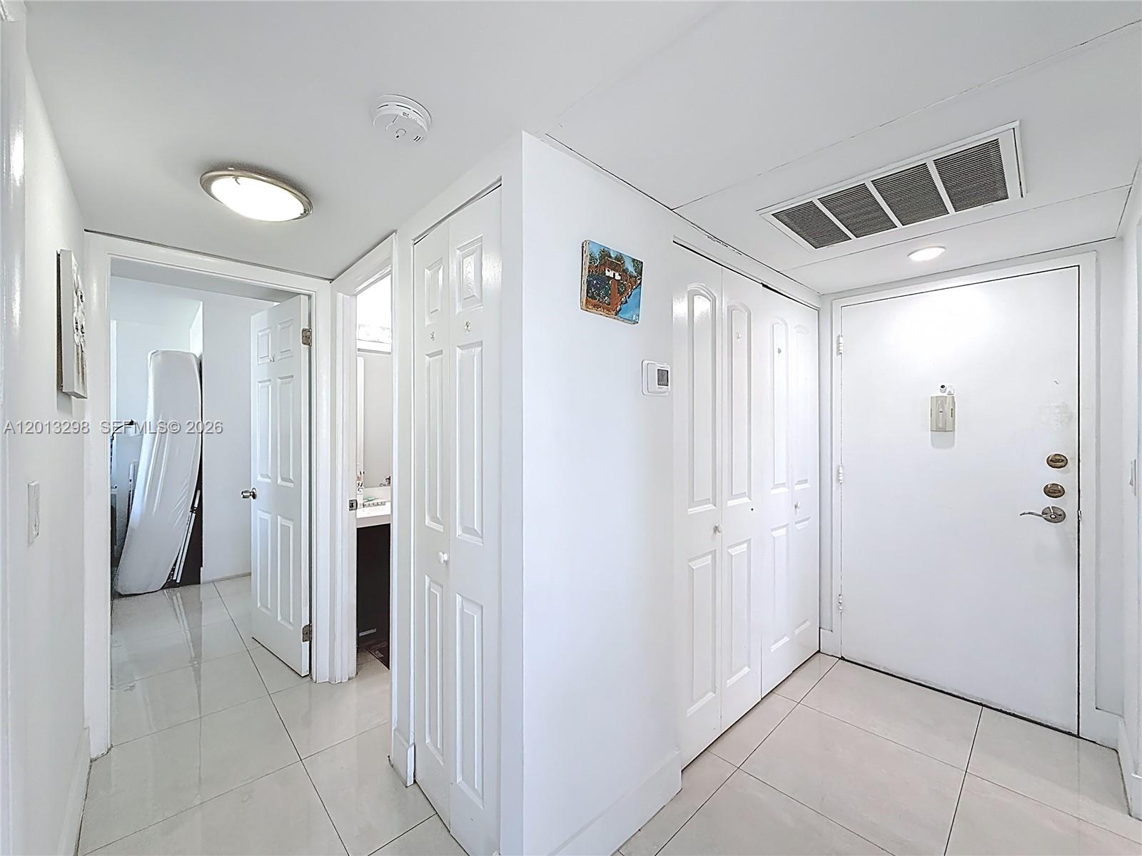 An interior hallway features white tile floors, multiple closet doors, and access to a bathroom — 2751 Taft St # 304, Hollywood FL 33020, HOLLYWOOD, FL