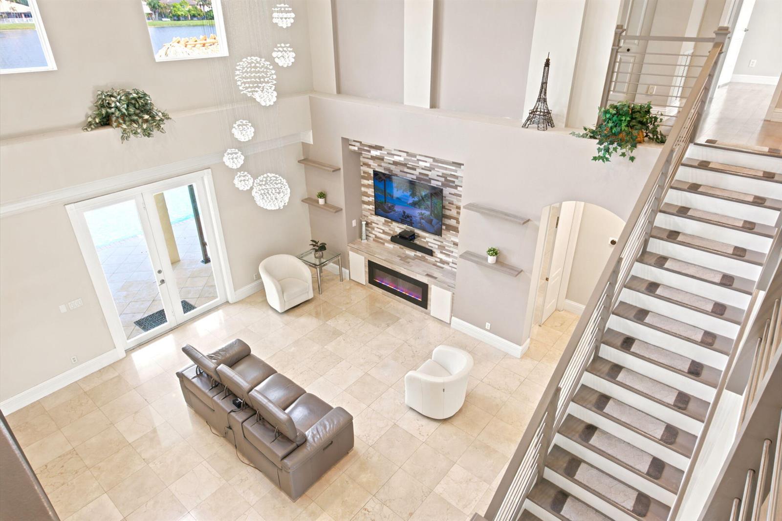 A high-angle view of a living room with a fireplace, staircase, and tile flooring — 3766 W Gardenia Avenue, Weston FL 33332, WESTON, FL