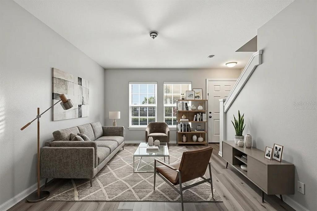 A living room with gray walls, wood-look flooring, a sofa, two chairs, and a bookshelf — 13157 THOROUGHBRED LOOP, LARGO, FL